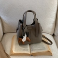 Detail of grey lychee leather bucket bag with horse charm on cream fleece sofa - With Pendant / Gray
