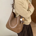 Borsa tote in pelle marrone con ciondoli indossata da una modella in stile autunno - Con Ciondolo / Marrone