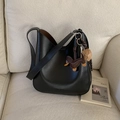 Borsa a tracolla in pelle nera opaca con ciondolo a bassotto su un divano crema - Con Ciondolo / Nero