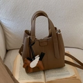 Brown lychee leather bucket bag with horse charm and crossbody strap on sofa - With Pendant / Brown