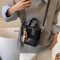 Sac seau rétro en cuir noir avec perles en bois, porté en bandoulière élégante sur un mannequin - Noir