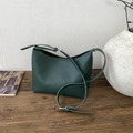 Bolso tipo cubo minimalista de cuero verde oscuro con hebilla plateada sobre madera - Verde