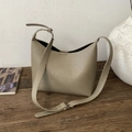 Bolso tipo cubo minimalista en cuero taupe con correa ajustable sobre base de madera - Caqui