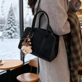 Black vintage tote bag with plush dog charm and leopard bow in a cozy winter setting - Black with Pendant