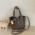 Close-up of pebble leather bucket bag with silver hardware and horse charm - With Charm / Gray