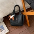 Close-up of black litchi pattern bucket bag with silver metal lock and horse charm - With Charm / Black