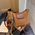 Retro brown dumpling bag with chain strap and cute bear charm in a cozy indoor setting - With Charm / Brown