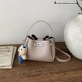 Détail du sac seau en cuir beige avec fermoir rotatif en métal et breloque ourson - Avec Pendentif / Khaki