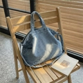 Sac fourre-tout en denim bleu clair avec bandoulière réglable sur une chaise - Bleu clair