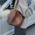 Sac cabas marron en cuir grainé avec bandoulière porté par un mannequin en extérieur - Marron