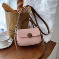 Primer plano del bolso bandolera rosa texturizado con asa de cuero marrón y botón - Rosa