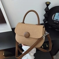 Detalle de bolso tejido retro con asa de cuero marrón y cierre de botón circular - Caqui