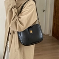 Bolso hobo minimalista de cuero negro con cierre dorado sobre una gabardina caqui - Negro