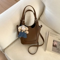 Detailed texture of brown litchi grain bucket bag featuring a cute teddy bear pendant - Brown with Pendant