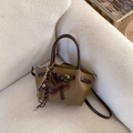 Mini olive green bucket bag with brown handles and a dachshund charm on a white sofa - Brown with Pendant