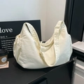 Close-up of cream nylon dumpling bag with adjustable wide strap on a minimalist display - White