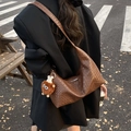 Braune gewebte Hobo-Tasche mit Bärenanhänger in einer modischen Streetstyle-Ansicht - Braun mit Anhänger