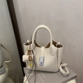 Bolso tipo bucket en cuero lichi blanco crema con cierre plateado y dijes - Beige