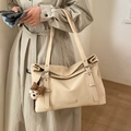 Detail of beige large tote bag showing metal Fashion logo and cute bear pendant charm - White with Pendant