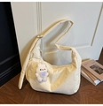 Détail du sac croissant crème avec breloque lapin dans un intérieur de maison cosy - Beige Avec Charme