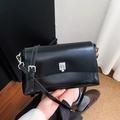 Detail of minimalist black leather crossbody bag featuring a silver rectangular twist lock - Black