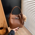 Detail of dark brown woven bucket bag with metal clasp and plush bear charm accent - Brown (With Bear Pendant)