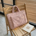 Sac pour ordinateur en velours côtelé rose avec poche avant sur une chaise - Rose