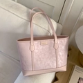 Pink marbled faux leather tote bag with gold logo plate displayed on a beige sofa - Pink