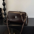 Retro dark brown crossbody bag with silver square clasp on a minimalist black cabinet - Brown