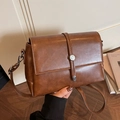 Borsa a tracolla vintage in pelle marrone con patta e fibbia su fondo caldo - Marrone
