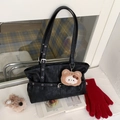 Detail of black leather tote bag with metal eyelet straps and plush bear charm - Black