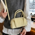 Bolso bowling de cuero amarillo pálido con asas y bandolera presentado en una cafetería - Amarillo