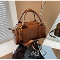 Detailed view of brown leather Boston bag with vintage gold buckles and side strap design - Brown