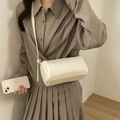Chic beige lychee textured cylindrical crossbody bag styled with a minimalist outfit - White