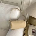 Close-up of cream Boston bag with lychee texture on a soft sofa with magazine decor - Khaki