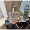 Detail der silbernen Mini-Beuteltasche mit Karomuster, grünem Band und Tulpenanhänger - Silber