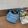 Détail du sac bandoulière en denim bleu clair avec doubles poches zippées et nœud latéral - Bleu clair