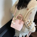 Bolso cubo de cuadros rosas con colgante de tulipán y lazo en el hombro de modelo - Rosa