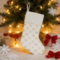 Gros plan d'une botte de Noël en velours blanc avec nœuds dorés sur un sapin de Noël - Blanc