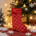 Détail d'une chaussette de Noël en velours rouge avec motifs de nœuds dorés festifs - Rouge