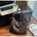 Detailed close-up of leopard print crossbody bag with black tassel on a leather bench - Coffee