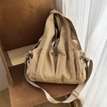 Minimalist beige nylon tote bag with wide shoulder strap on wooden chair - Khaki