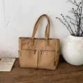 Detailed view of khaki canvas tote bag with functional pockets on a rustic wooden desk - Caramel color
