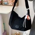 Black matte suede hobo tote bag with cartoon plush pendants and logo patch detail - With Charm / Black