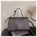 Détail d'un sac cabas en cuir marron foncé à grain litchi avec fermoir doré sur livres - Marron