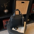 Borsa classica in ecopelle nera con tracolla regolabile su un tavolo vintage - Nero