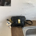 Detail einer schwarzen geflochtenen Handtasche mit Goldschnalle und Bärenanhänger - Schwarz (Mit Anhänger)