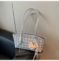 Detail of silver checkered tote bag featuring a plush bear charm on a leather sofa - Silver