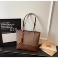 Detail of a brown patchwork tote bag with white stitching and vintage beaded charm - With Charm / Coffee