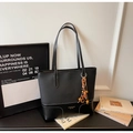 Detail of black leather tote bag with contrast stitching and bohemian beaded charm - With Charm / Black